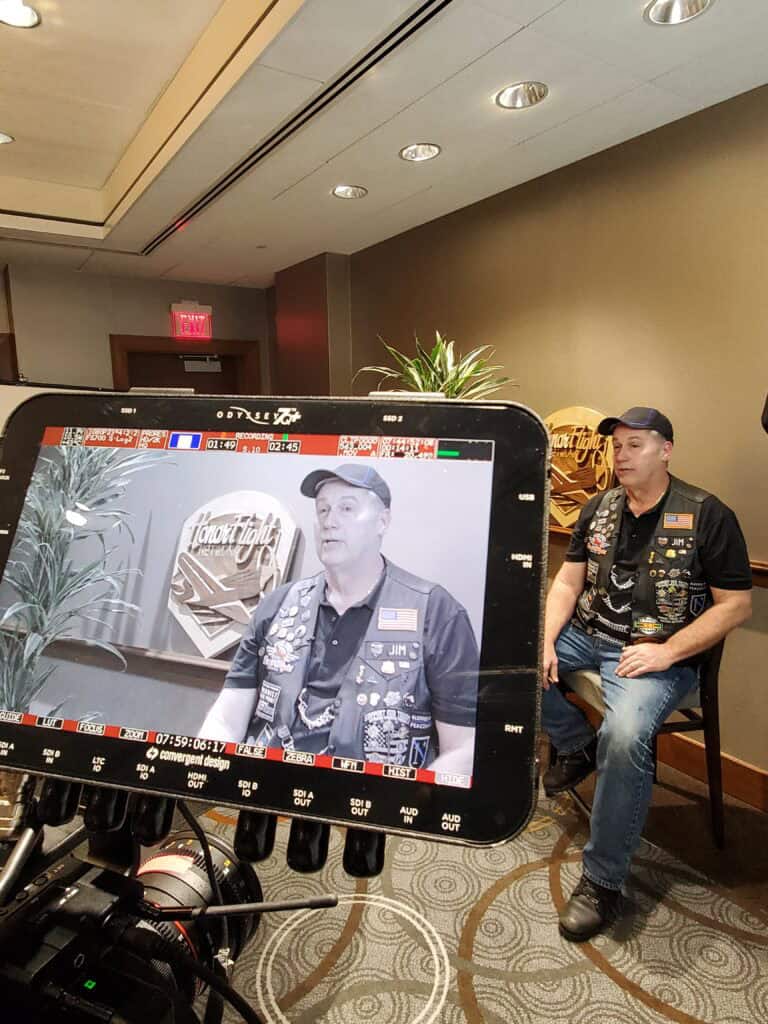 Vulnerable to typical thefts, a man in a black vest with patches and a baseball cap is being filmed in a close-up on a professional camera.