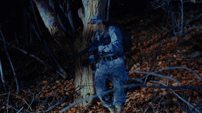 1. Soldier in camouflage gear patrolling a wooded area at night.